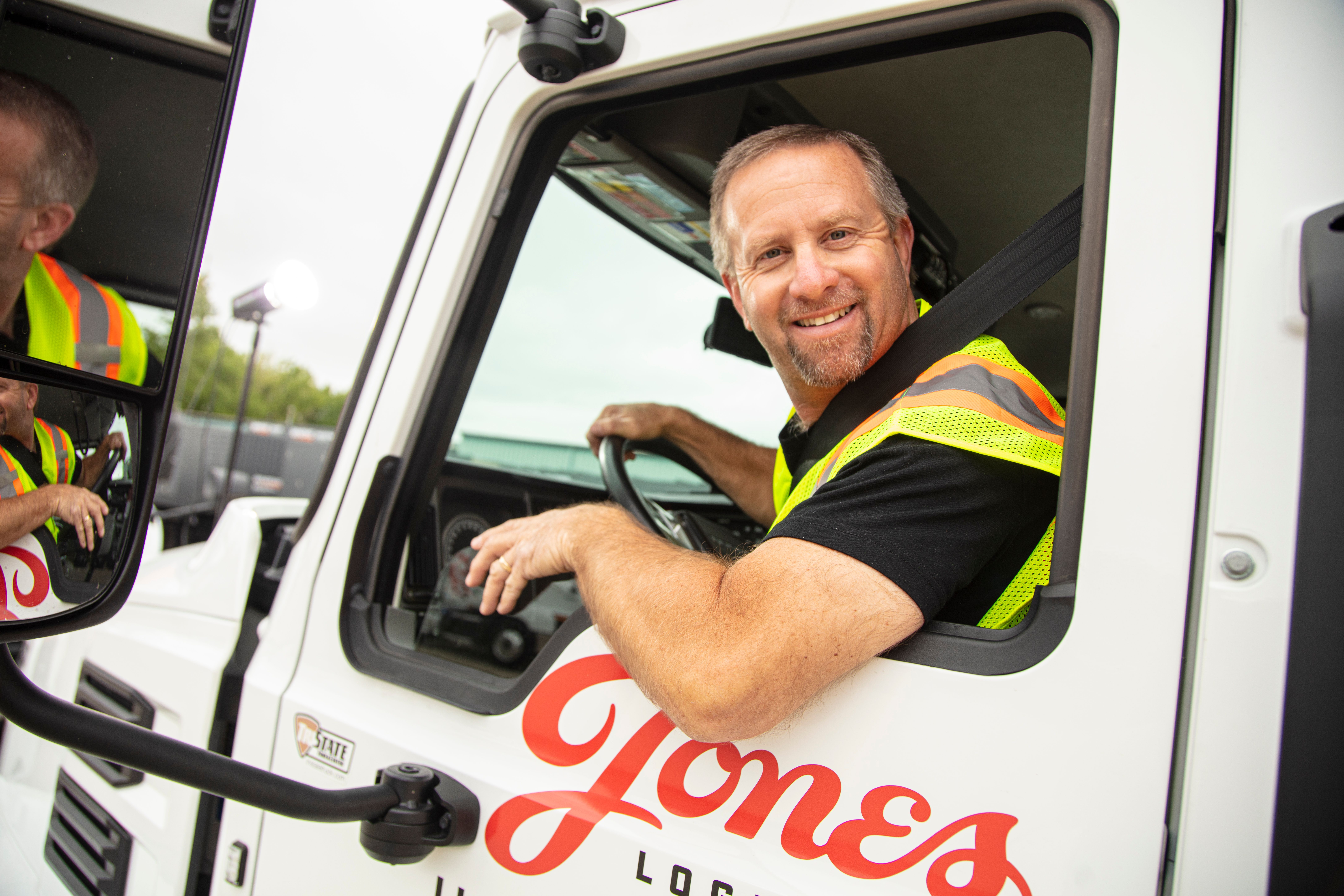 A Jones Logistics (JoLo) driver smiles at the camera from his truck as he heads out to deliver generators.