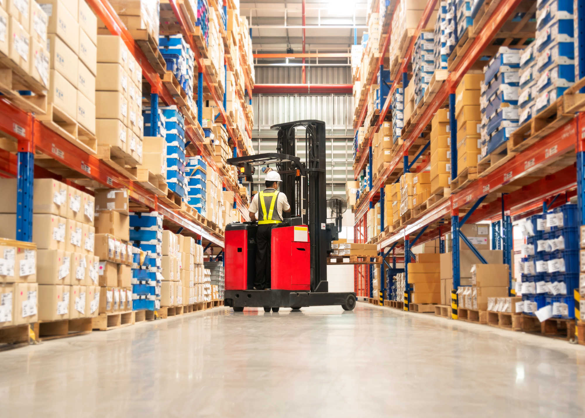 Forklift operator moves boxes through warehouse.