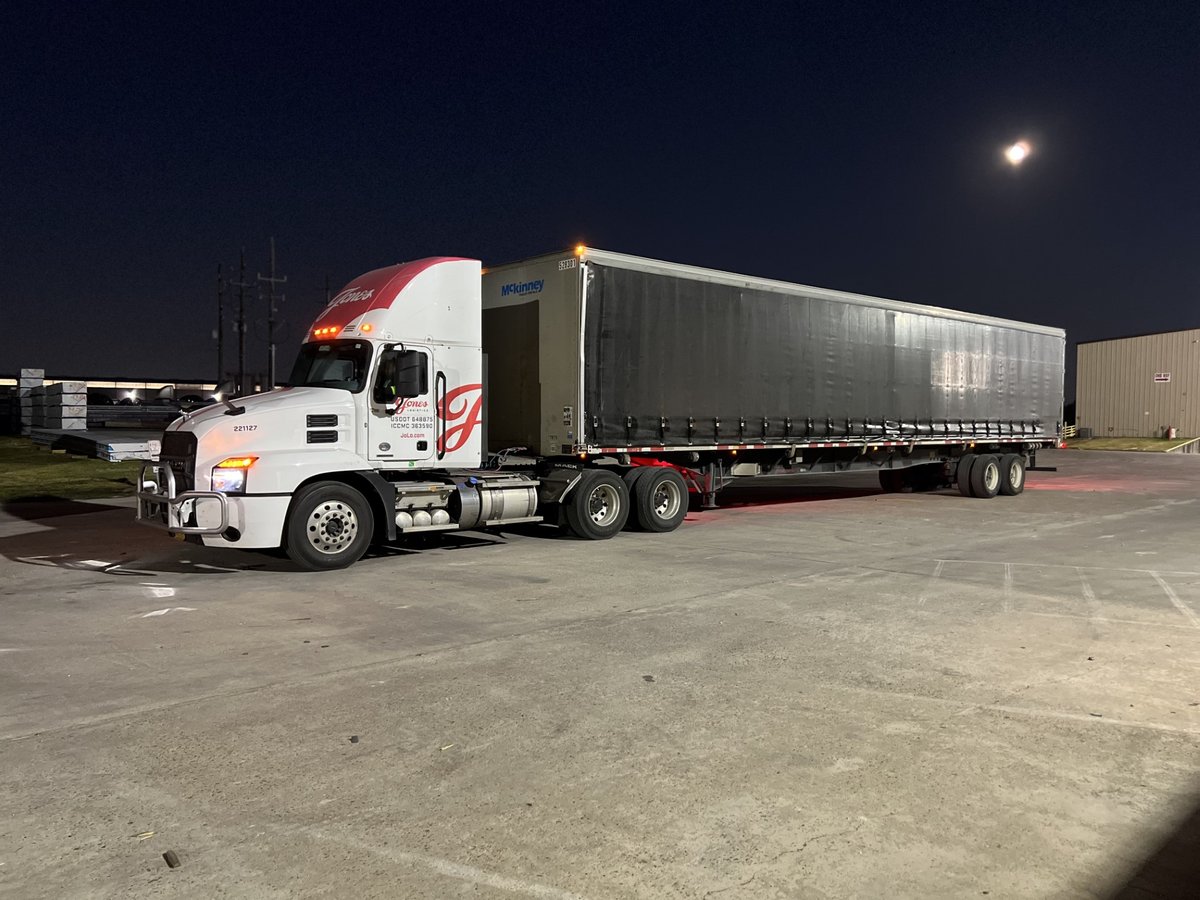 Jones Logistics (JoLo) conestoga trailer out for delivery in Texas at night.